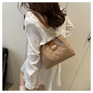 Detail of beige quilted shoulder bag with golden chain strap and metallic twist lock