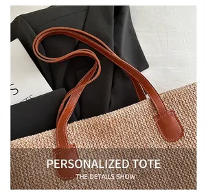Detail showing woven raffia texture and brown leather handle with white decorative stitching
