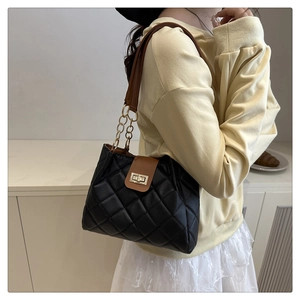 Détail du sac bandoulière matelassé noir avec fermoir doré et bandoulière marron