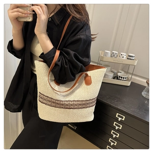 Detail of contrast striped woven tote bag with brown leather straps in a home setting