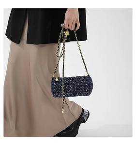 Détail du sac cylindre en tweed bleu marine avec chaîne dorée et texture matelassée