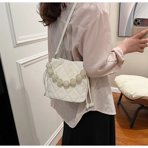 Détail du sac seau matelassé blanc avec poignée en perles marbrées et bandoulière