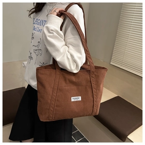 Detailed texture of brown corduroy tote bag showing fashion instinct label and long strap