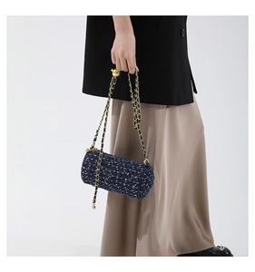 Détail du sac cylindrique en tweed bleu foncé avec ajusteur de chaîne en métal doré
