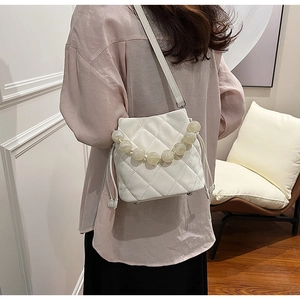 Détail d'un sac seau blanc matelassé avec poignée en perles et cordon de serrage chic