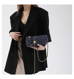 Détail d'un sac cylindre en tweed bleu avec chaîne dorée et sequins brillants