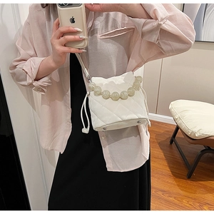 Détail du sac seau matelassé blanc avec de grandes perles décoratives et cordon