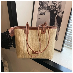 Detailed view of summer woven straw tote bag with brown leather handles and textured weave