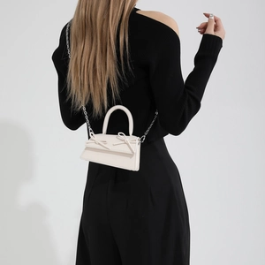 Chic cream white mini handbag with dual bows and silver chain strap shown on model