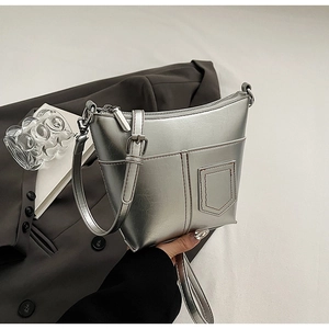 Silberne Metallic-Beuteltasche im Detail mit Kontrastnähten und verstellbarem Schultergurt