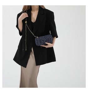 Détail du sac cylindre en tweed bleu avec chaîne dorée et accents de boules métalliques
