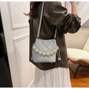 Détail d'un sac seau matelassé bleu clair avec poignée en perles et clous de protection