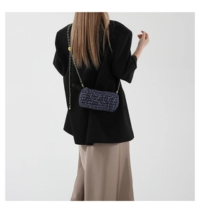 Détail d'un sac cylindre en denim bleu avec bandoulière chaîne dorée sur mannequin