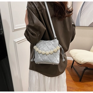 Détail du sac seau en velours matelassé gris clair avec poignée décorative en perles