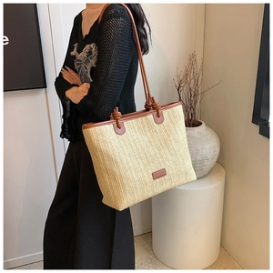 Detail of woven tote bag with brown leather shoulder straps and stylish knot accents