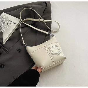 Detail der cremeweißen minimalistischen Bucket Bag mit feiner Textur und Nähten auf Blazer