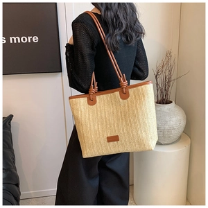 Detail of woven straw tote bag with brown leather straps and knotted accents for women