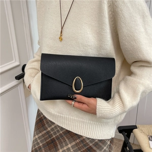 Sac bandoulière enveloppe noir pour femme avec boucle dorée porté par un mannequin