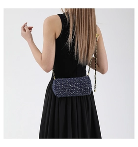 Détail du sac cylindre en tweed bleu avec chaîne dorée porté par un mannequin
