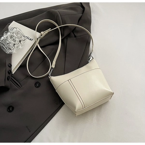 Detail einer minimalistischen beigen Ledertasche mit vertikalen Nähten und Schultergurt