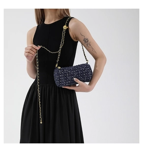 Détail du sac cylindrique en tweed bleu avec chaîne dorée et boucle à boule ajustable