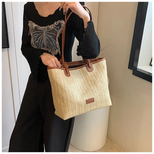 Detail of hand-woven summer tote bag with brown leather shoulder straps and rectangular patch