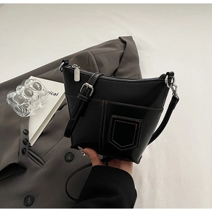 Detail der schwarzen Beuteltasche mit Kontrastnähten auf einem grauen Blazer