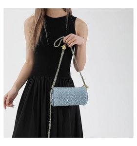 Détail du sac cylindre bleu clair avec texture en tweed et bandoulière chaîne dorée