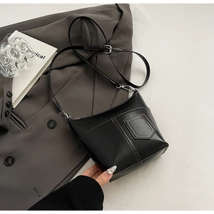 Detail der schwarzen Bucket-Bag mit braunen Kontrastnähten und Metallbeschlägen