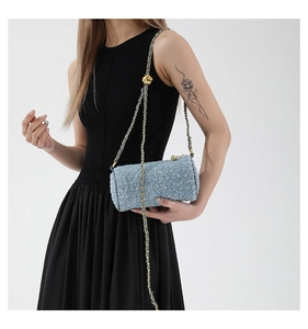 Détail du sac cylindre en denim bleu avec bandoulière en chaîne métallique bicolore