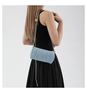 Détail du sac cylindre à paillettes bleu clair avec chaîne dorée porté par un mannequin