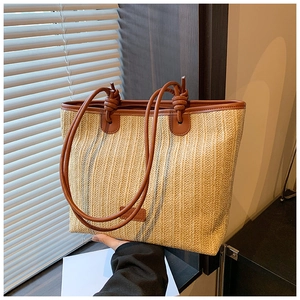 Detail of woven straw tote bag with brown leather handles and natural texture