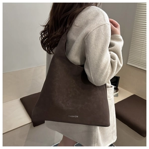 Dettaglio di una borsa tote in pelle scamosciata marrone scuro con logo FASHION argentato