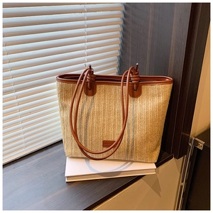 Detailed close-up of woven straw tote bag with blue stripes and brown leather straps