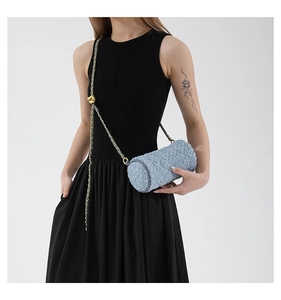 Détail du sac cylindre en jean bleu clair avec chaîne dorée et boucle à boule dorée
