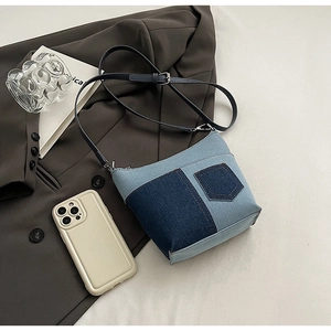 Detailansicht der Denim-Beuteltasche aus Patchwork-Stoff auf einem braunen Sakko