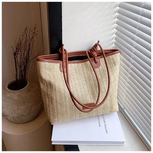 Close-up of woven straw handbag with brown leather knotted handles and textured details