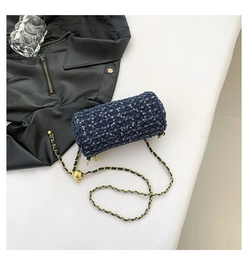 Détail du sac cylindre en tweed bleu marine avec chaîne dorée et boucle réglable dorée