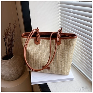 Detail of woven straw tote bag with brown leather handles and decorative leather knot