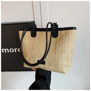 Detailed shot of straw tote bag with black leather trim and contrasting woven texture