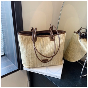 Close-up of woven straw tote bag with brown leather handles and textured vertical pattern