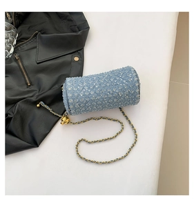 Détail du sac cylindre en jean bleu clair avec sequins argentés et chaîne dorée