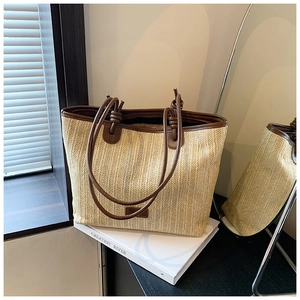 Detail of hand-woven straw tote with premium brown leather handles and brand tag