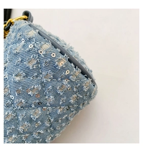 Détail du tissu denim matelassé avec des paillettes argentées et des bords effilés