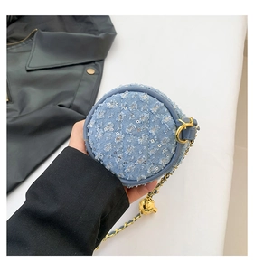Détail d'un mini sac en denim bleu matelassé avec sequins argentés et chaîne dorée