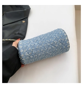 Détail macro du sac baril en denim bleu clair avec matelassage en losange et paillettes