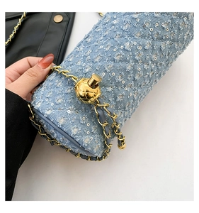 Détail du sac cylindre en denim bleu avec surpiqûres, paillettes et boucle boule dorée