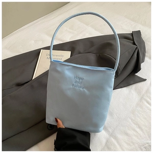 Primer plano detallado de un bolso tipo cubo azul con bordado Hope and Future chic