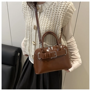 Bolso de cuero sintético marrón con hebilla plateada en un entorno de estilo de vida