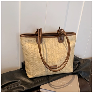 Close-up of woven straw tote bag with premium brown leather handles and textured finish